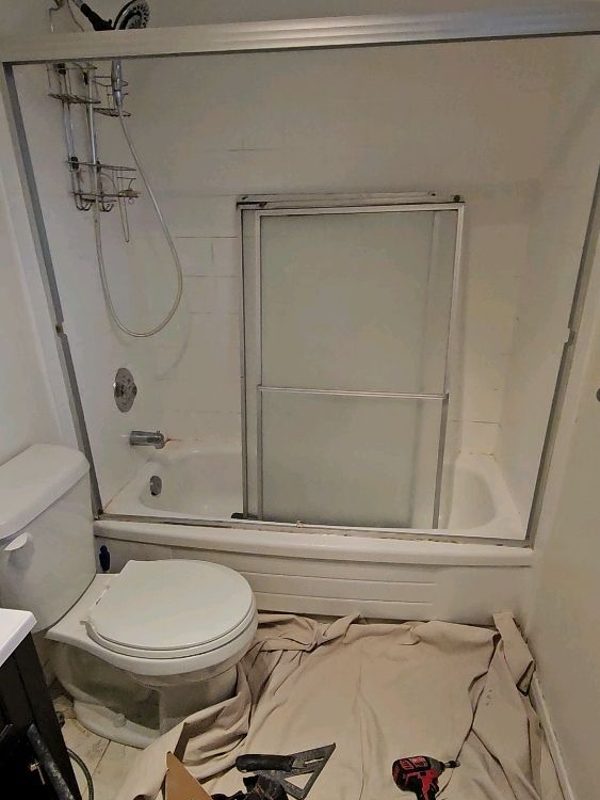 Bathroom before renovation — old tub and dated sliding-door shower